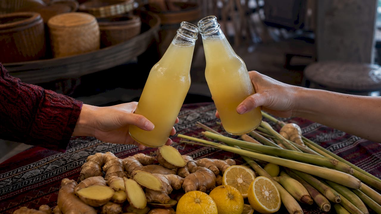 Clinking ginger-lemongrass kombucha bottles in café