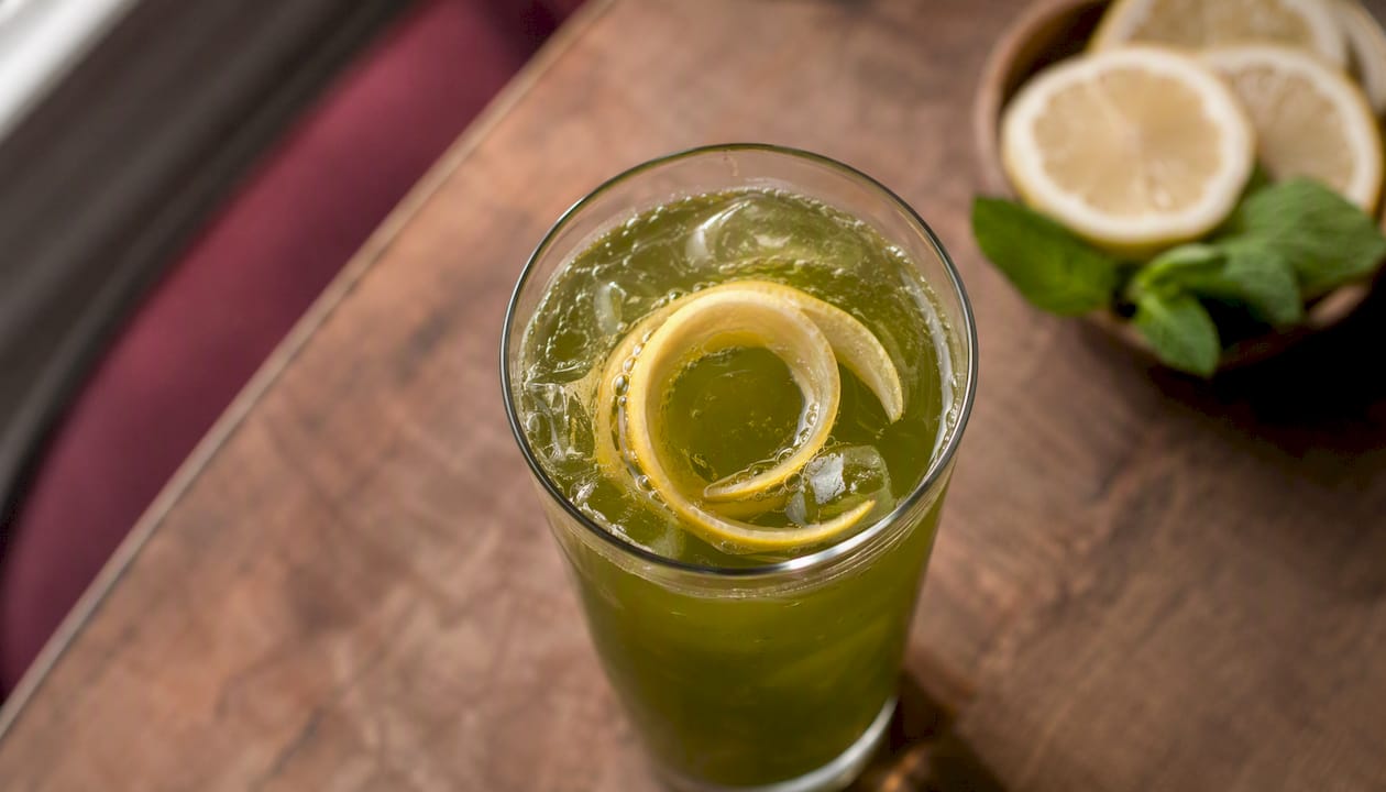 Glass of cold-brewed green tea spritz with lemon peel
